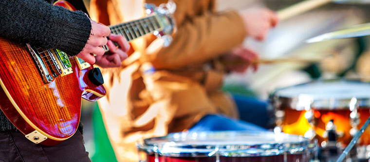 People playing guitar and drums at a music festival