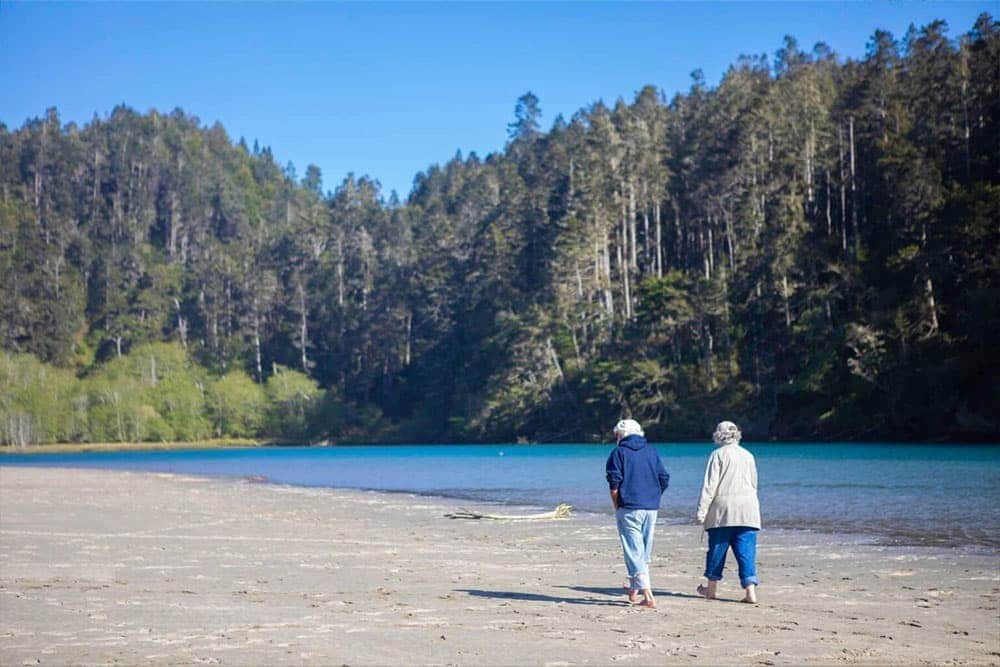 Senior couple walking along a Mendocino coast beach near Dennen's Victorian Farmhouse Inn - AARP member discount